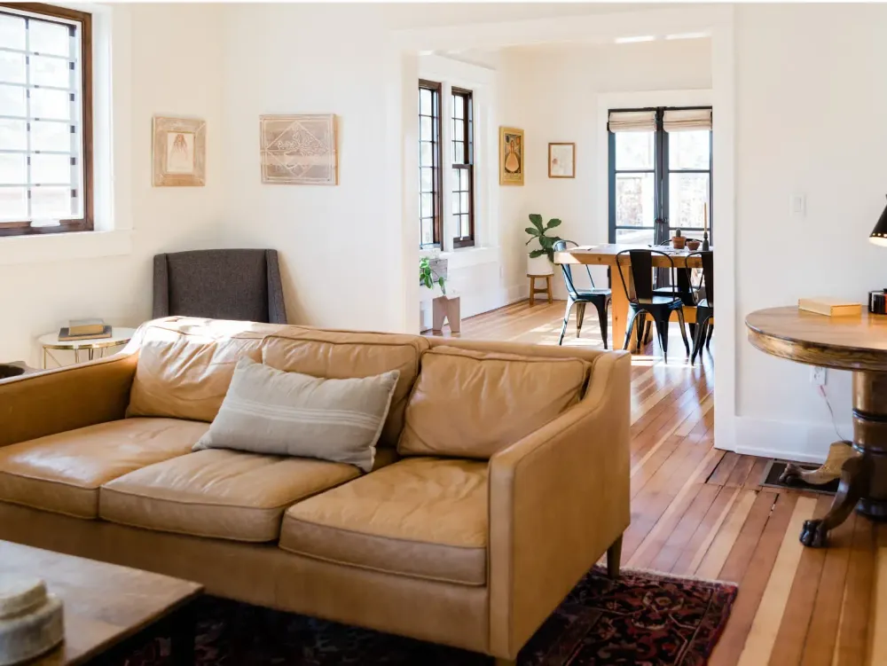 Living room with a tan leather couch in the foreground.